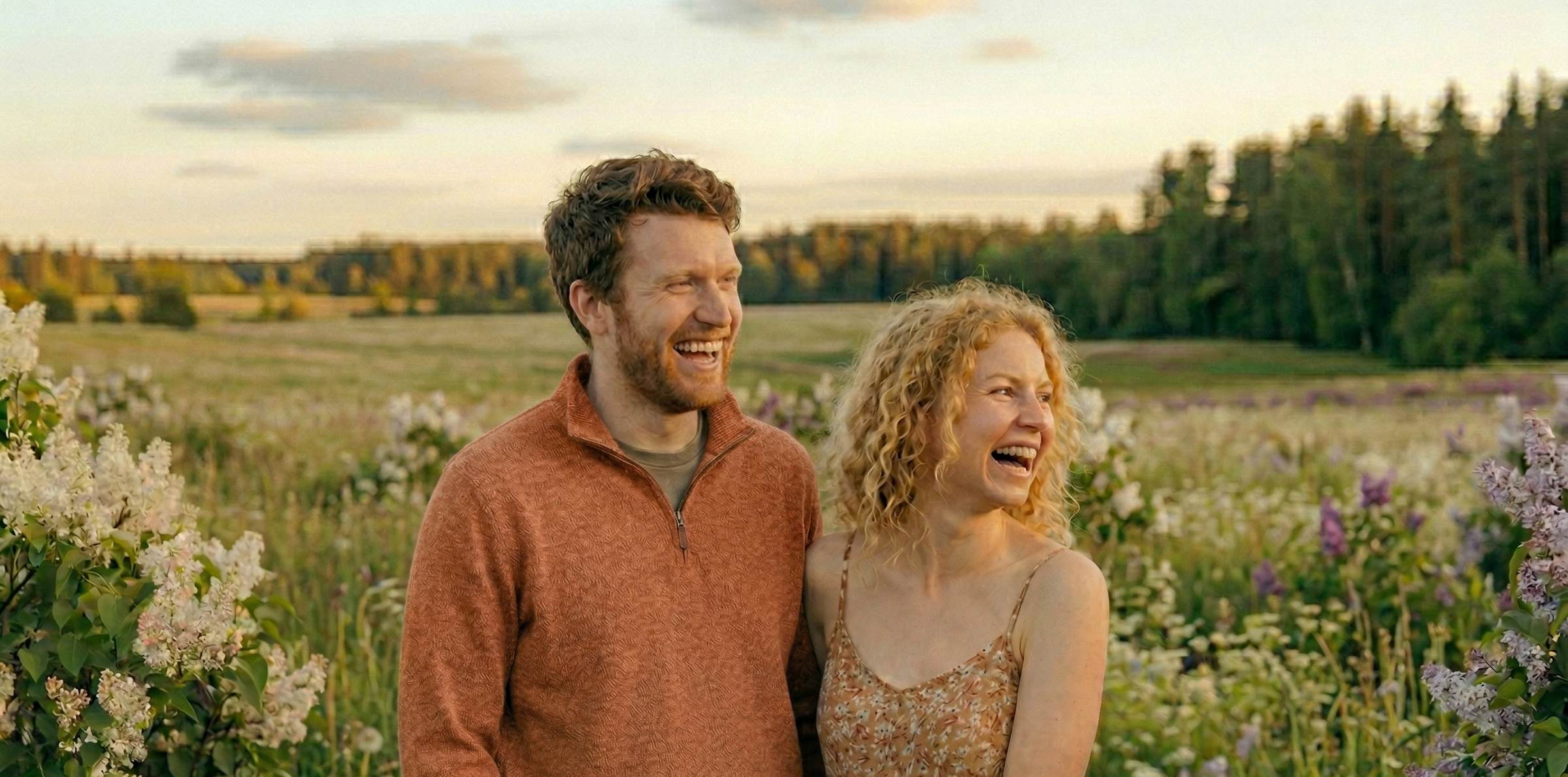 Man and woman standing in a field of flowers with a scenic background