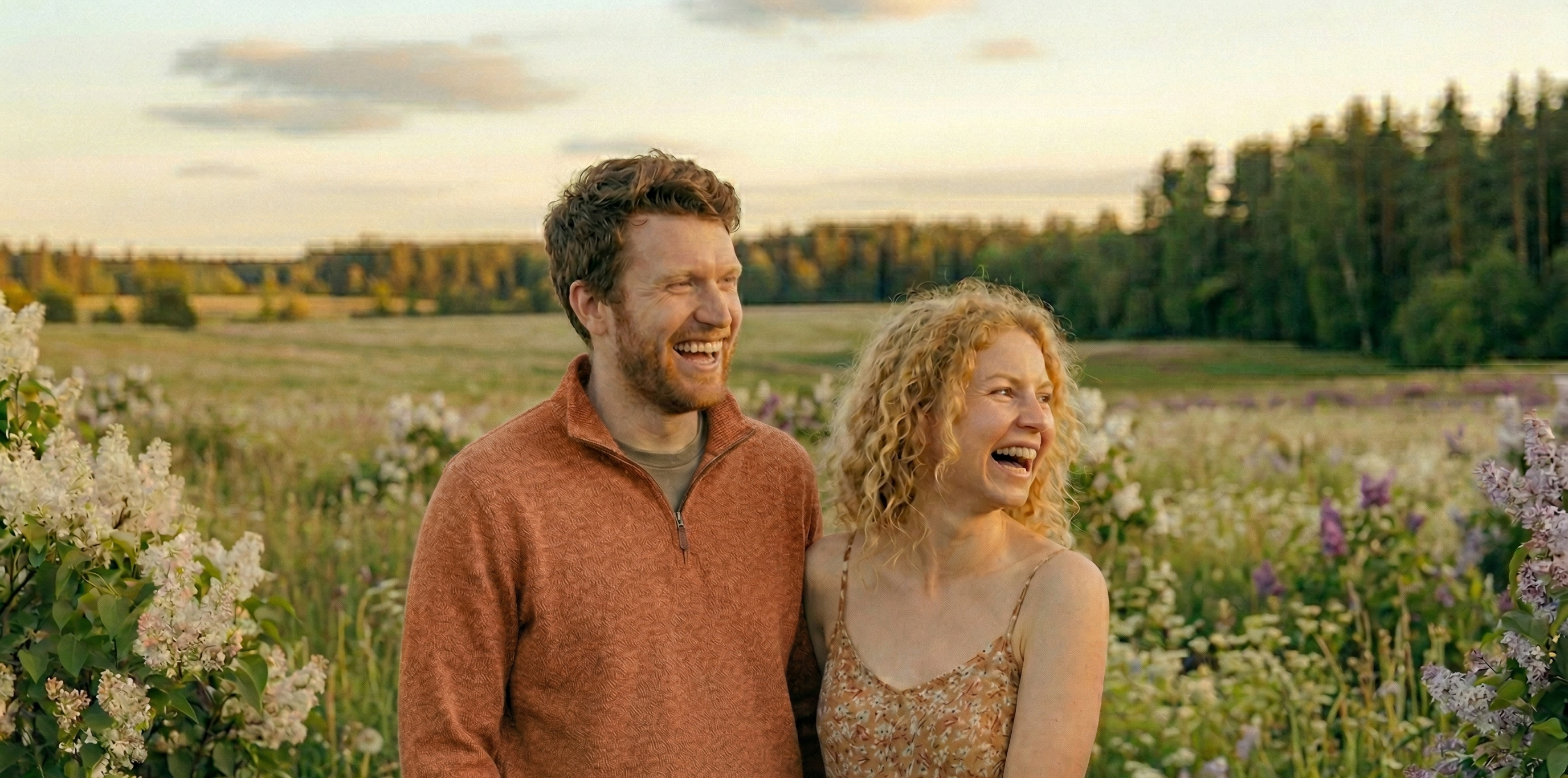 Man and woman standing in a field of flowers with a scenic background
