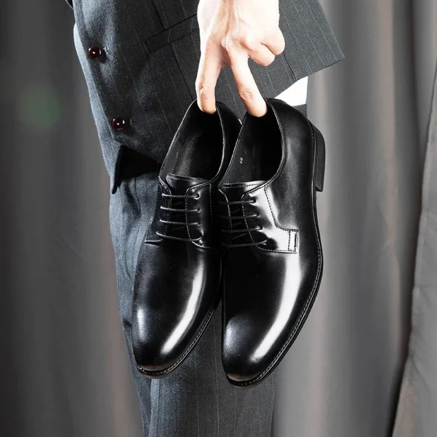 Czarne buty derby ze sznurowaniem trzymane w dłoni
